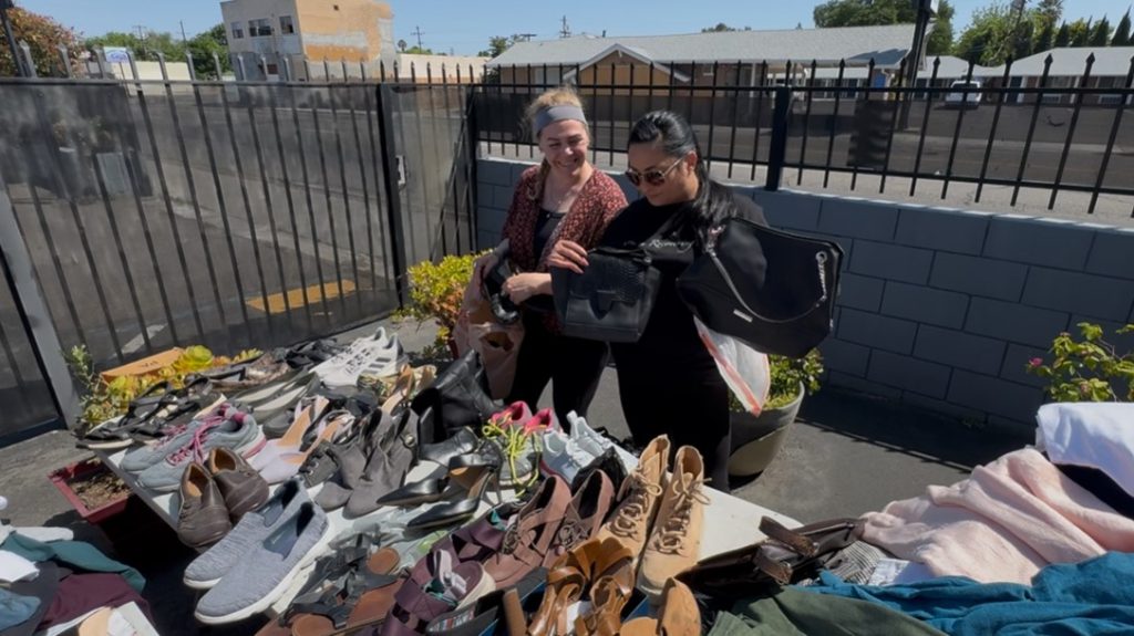 Two FCRP participants go through clothing on a table in Stockton.