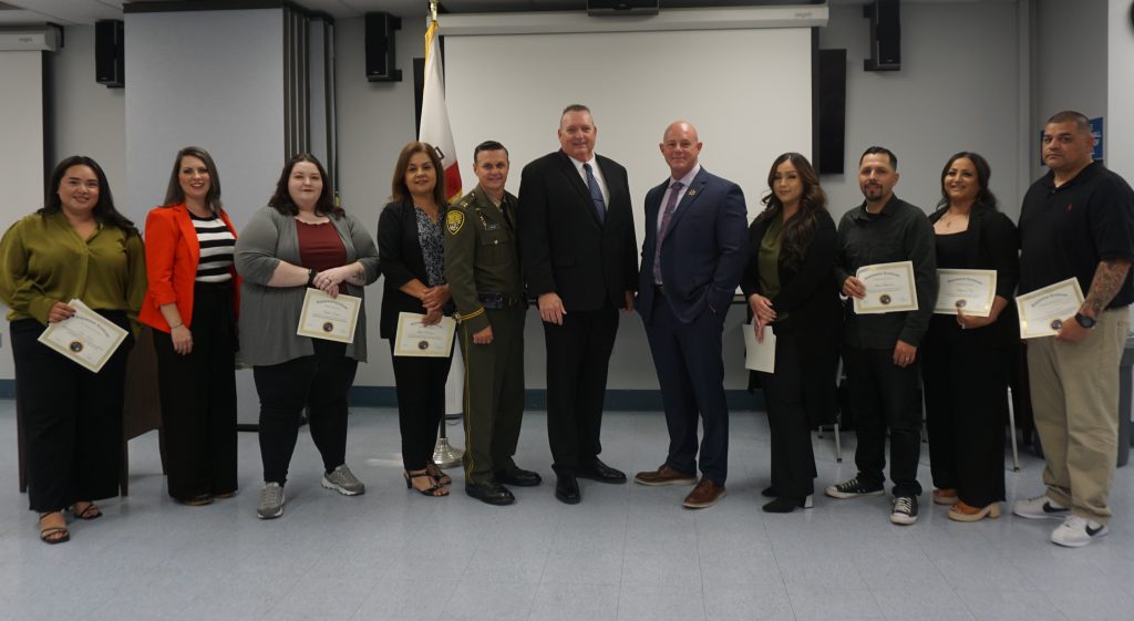 Kern Valley State Prison staff posing for the camera with the Warden, holding their promotional certificates