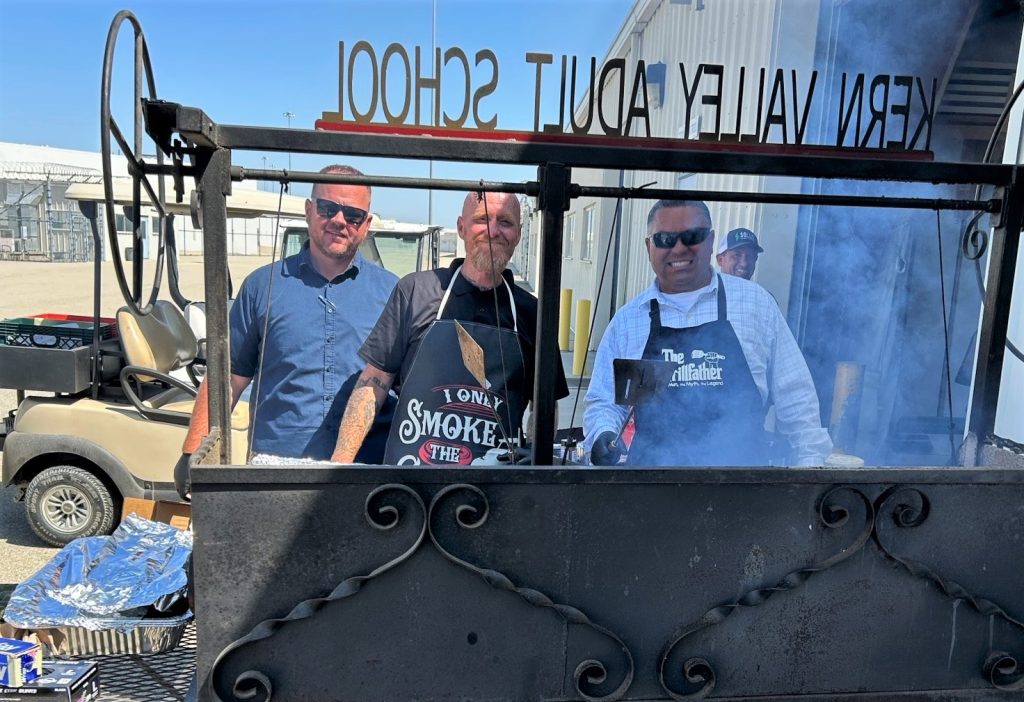 Three people work the barbecue at Kern Valley State Prison for National Skilled Trades Day.