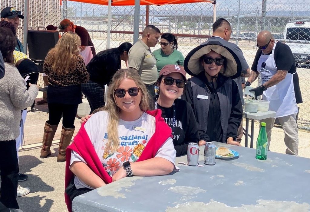 Three people sitting a table during a staff appreciation delegation celebration at CSP-Los Angeles County in Lancaster, California. 