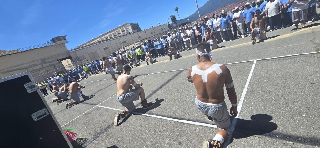 Traditional dancers, who are also incarcerated at San Quentin, kneeling before they begin.