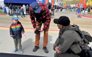 Recruiters at Sea Otter even in Monterey with a child speaking to a correctional officer.