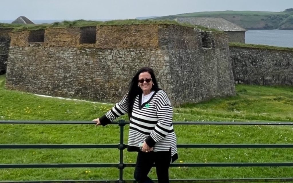 Supervising Registered Nurse II Anne Salzman posing in front of a rock building while on vacation.