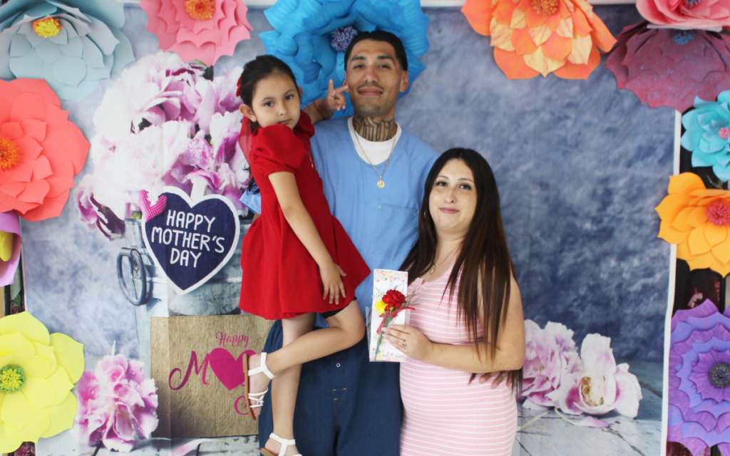 Mother's Day visiting at Centinela State Prison, Sunday, May 11, 2025, with an incarcerated person holding a child while a woman holds a card.