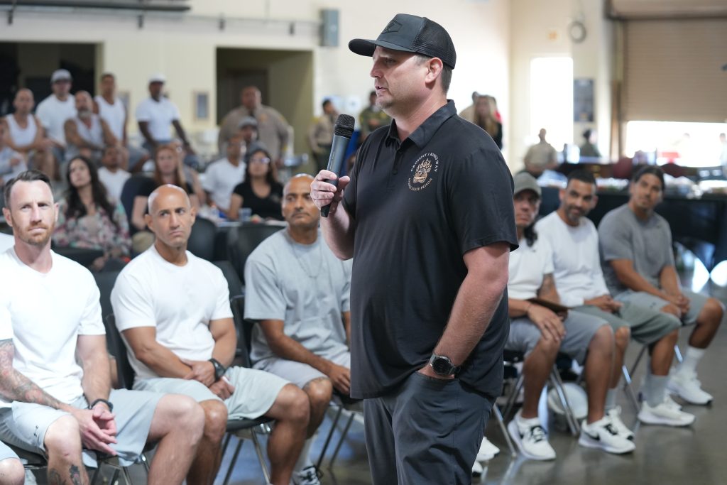 Avenal State Prison Coach Bryan Eskew speaks to a gathering of incarcerated people.