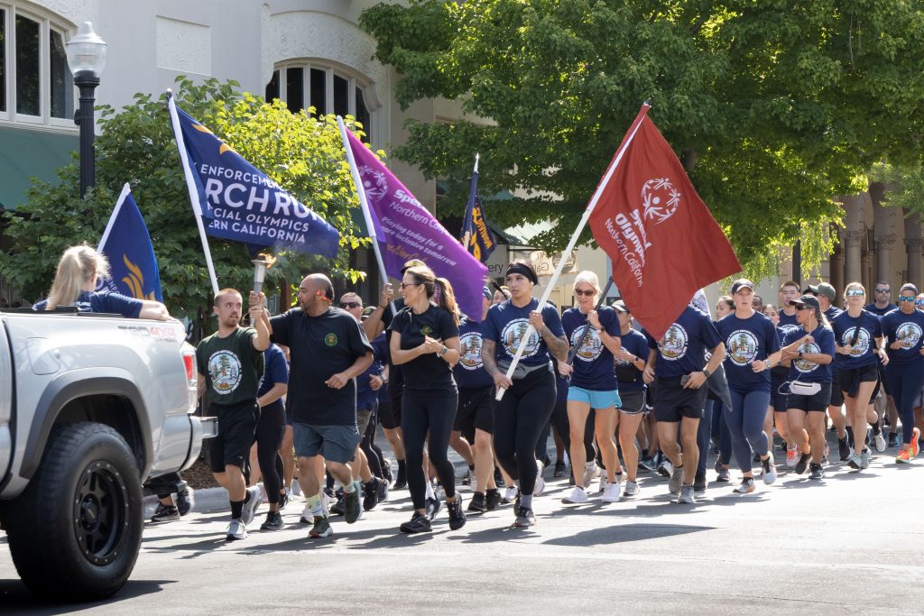 Volunteers from CDCR and CCHCS run with flags and the Flame of Hope during the Law Enforcement Torch Run benefiting Special Olympics.