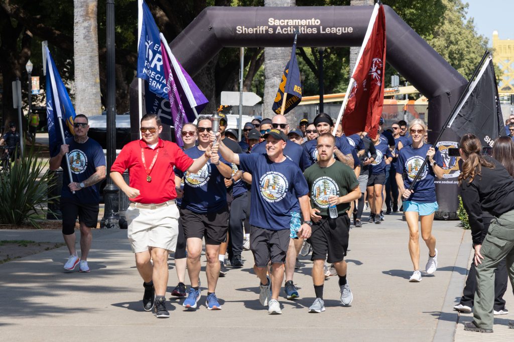 CDCR and CCHCS staff run with flags and the Flame of Hope during the Law Enforcement Torch Run benefiting Special Olympics.