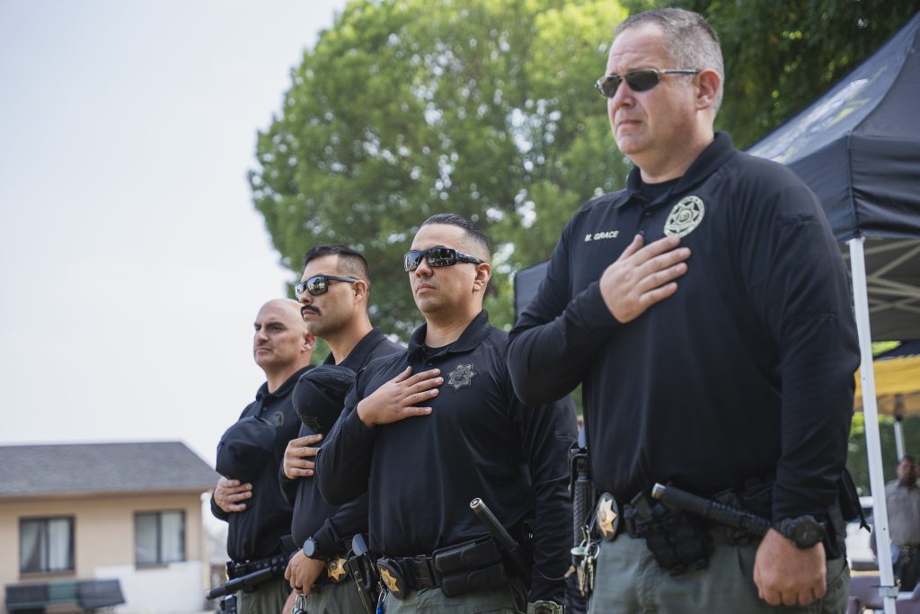 Officers place hands over hearts during the pledge of allegiance during the K-9 ceremony at CIM in Chino.