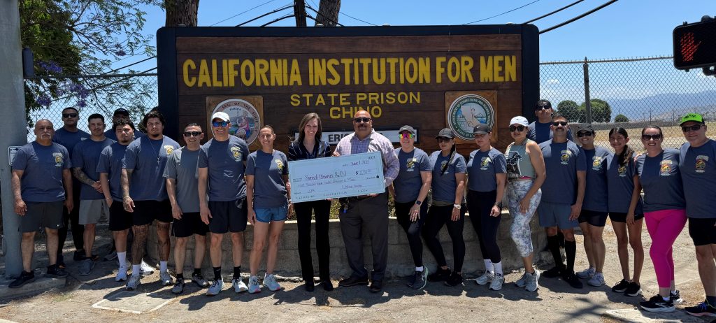 California institution for Men staff gathered in front of the sign while holding a check for the Law Enforcement Torch Run to benefit Special Olympics.