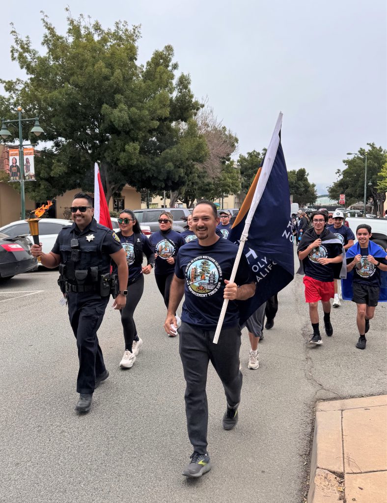 Runners carry the torch and flags at the Torch Run for Special Olympics.