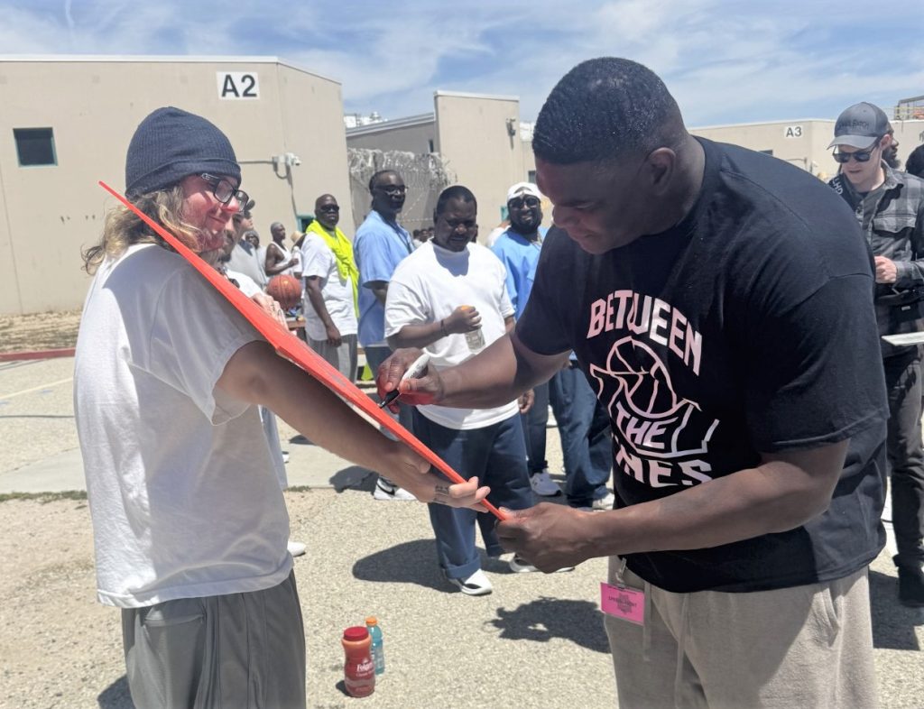 NFL legend Keshawn Johnson autographs a sign at LAC.