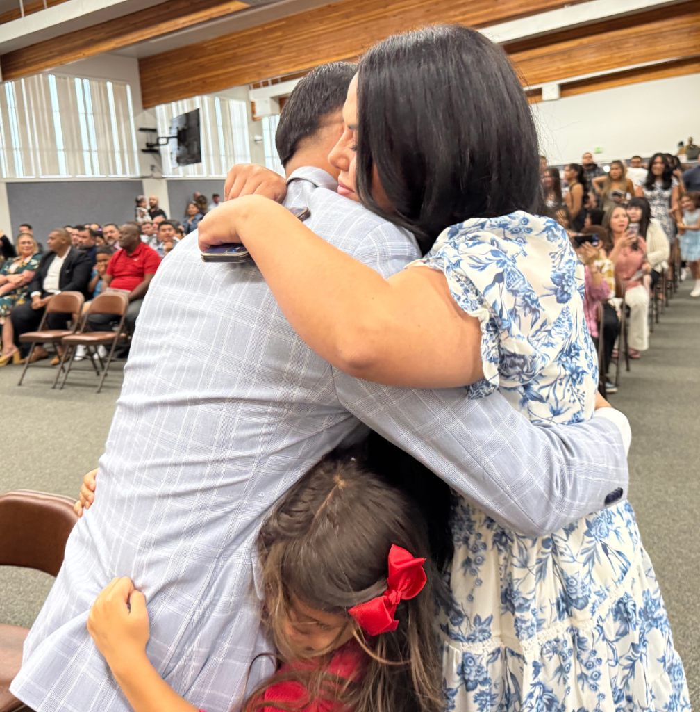 Mendoza his hugged by his wife and daughter at his parole agent graduation ceremony.