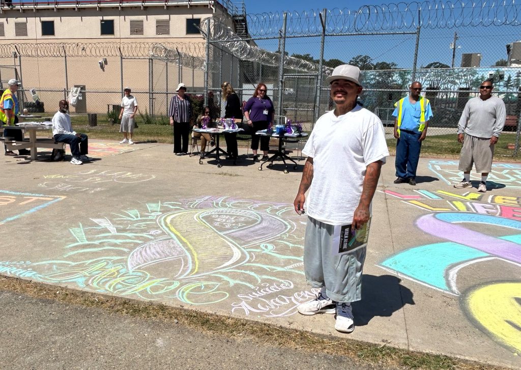 incarcerated person decorating pavement with chalk