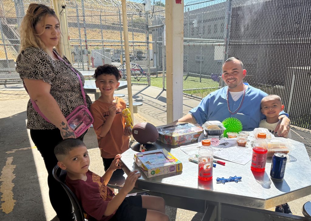 A family sits at a table at Folsom State Prison for a Fourth of July event.