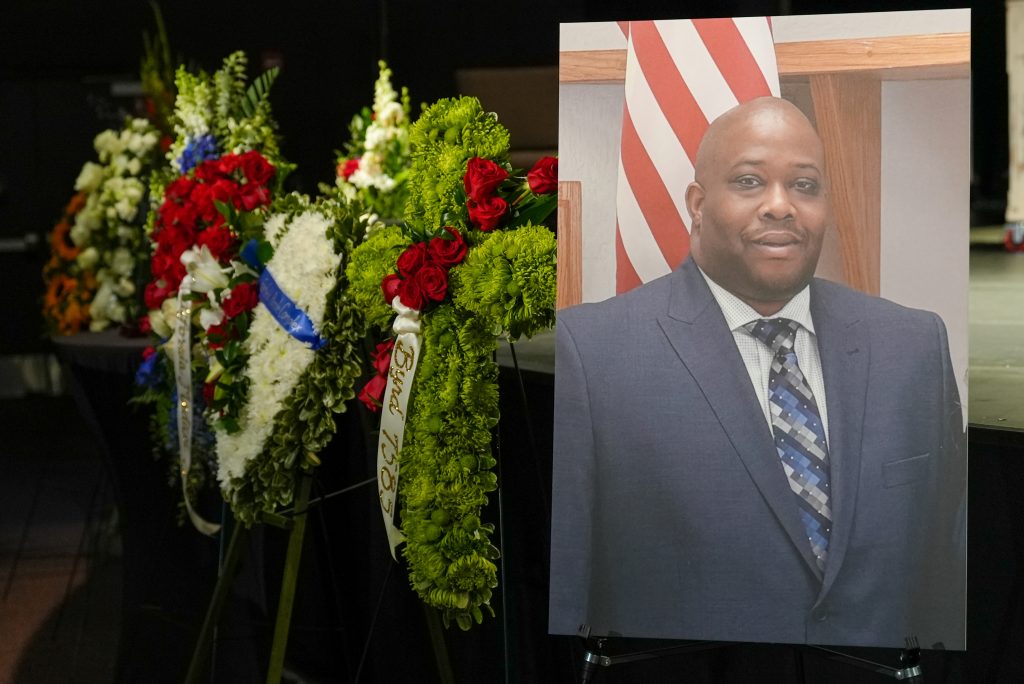 Parole Agent Joshua Byrd memorial service with flowers and a large photo of Byrd.