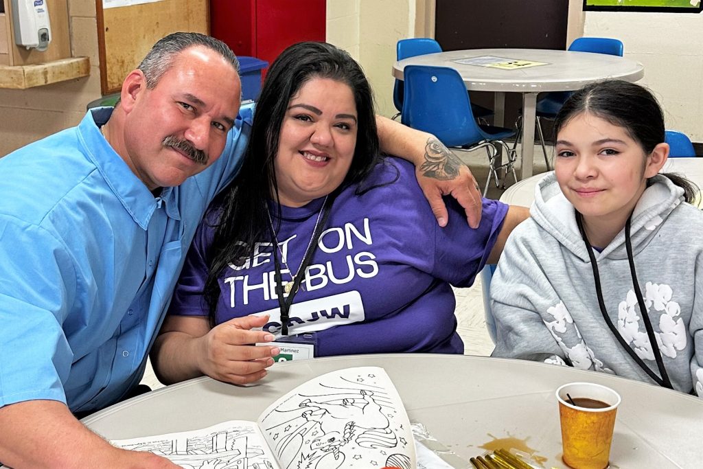 A family smiles while visiting during Get on the Bus, a prison program designed to strengthen family ties for incarcerated people and children.