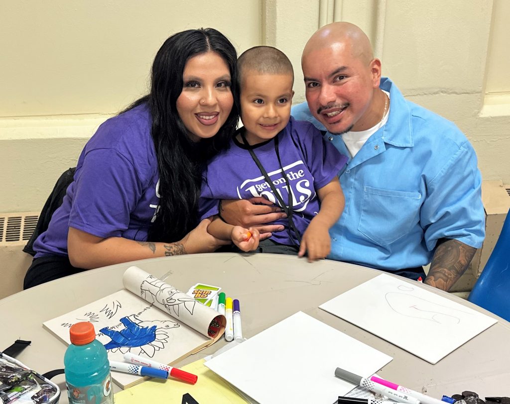 A family group photo with an incarcerated person, a child and a woman at CTF-Soledad, Calif., Aug. 2, 2025, as part of Get on the Bus.