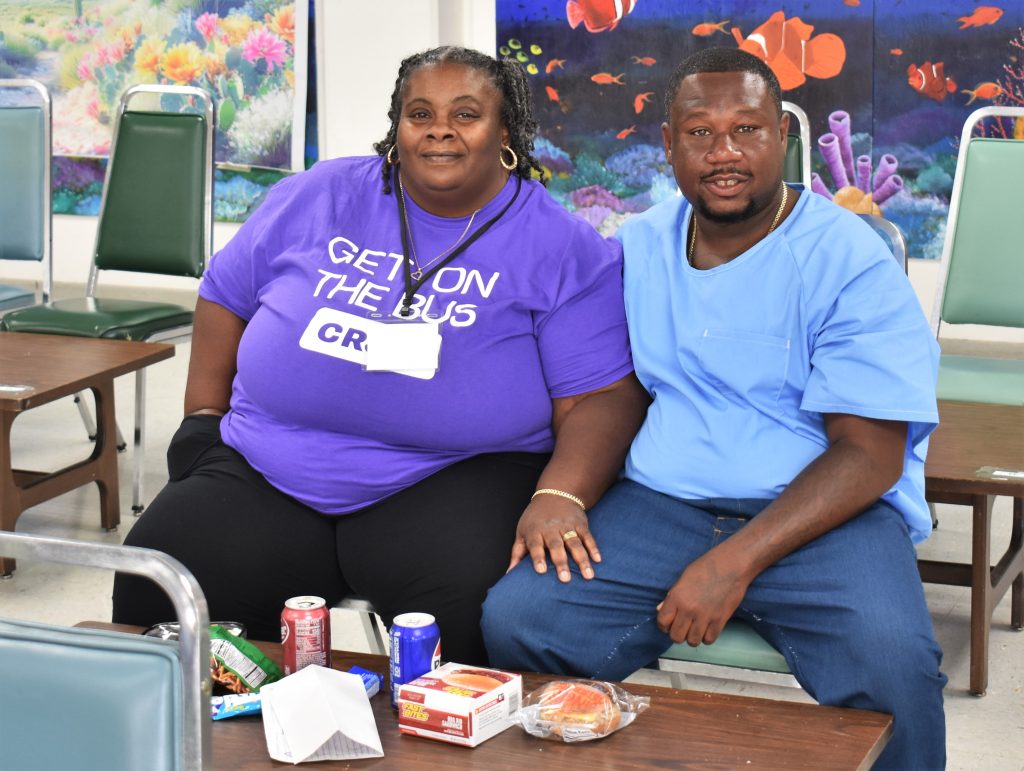 A woman visits an incarcerated man at Salinas Valley State Prison. She's wearing a Get on the Bus purple t-shirt.