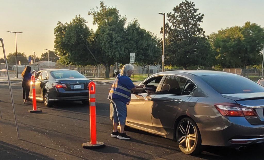 Volunteers hand out school supplies in a drive-through pick-up line.