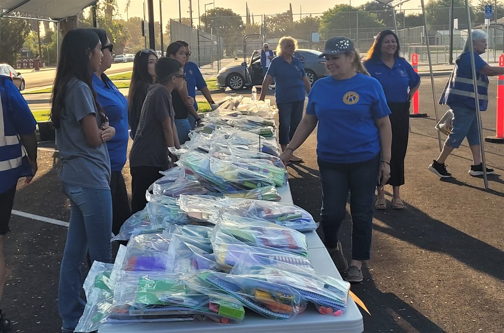 Volunteers with a table of back-to-school supplies, many donated by CSP-Corcoran staff.