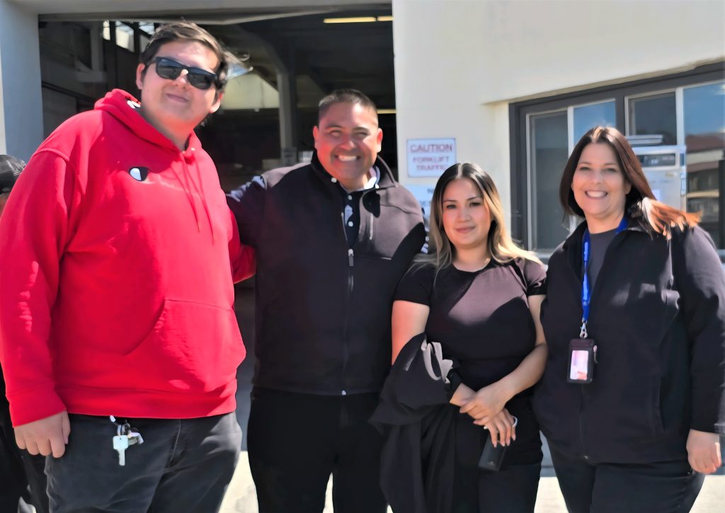 San Quentin staff, two men and two women, smile for the camera.
