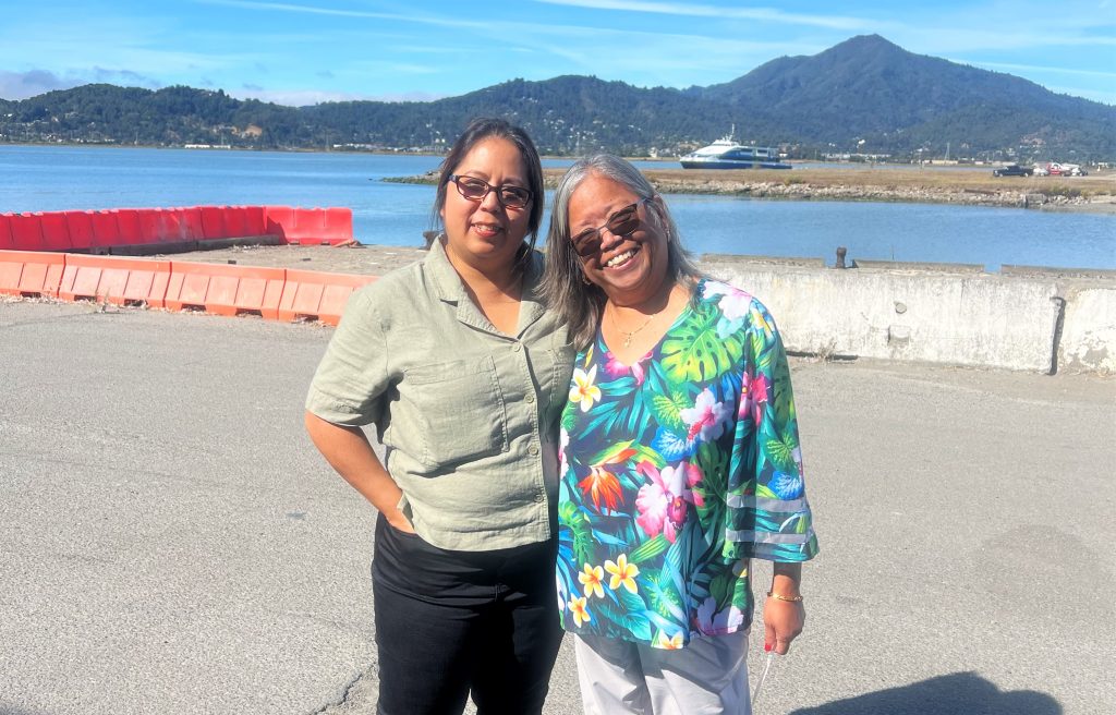 Two staff members pose for a photo with the bay behind them at San Quentin Rehabilition.