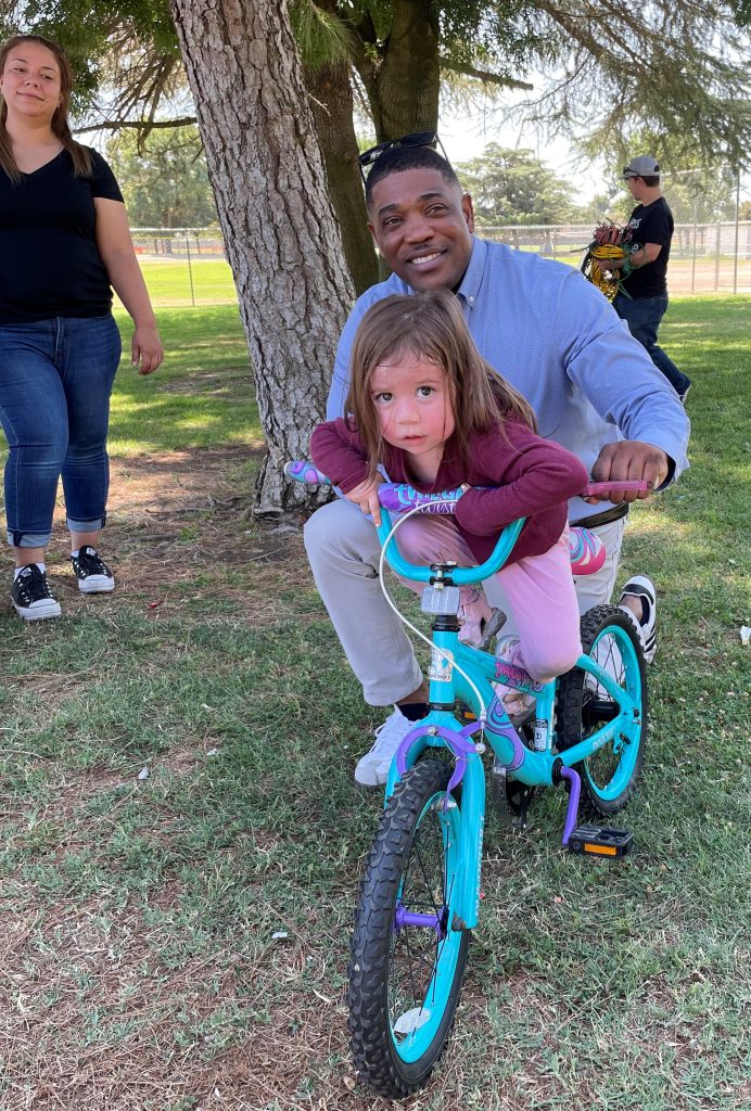 Acting Warden with a child and small bicycle.