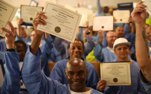 Incarcerated people hold certifications and diplomas at a graduation for CALPIA at California Men's Colony (CMC) in San Luis Obispo.