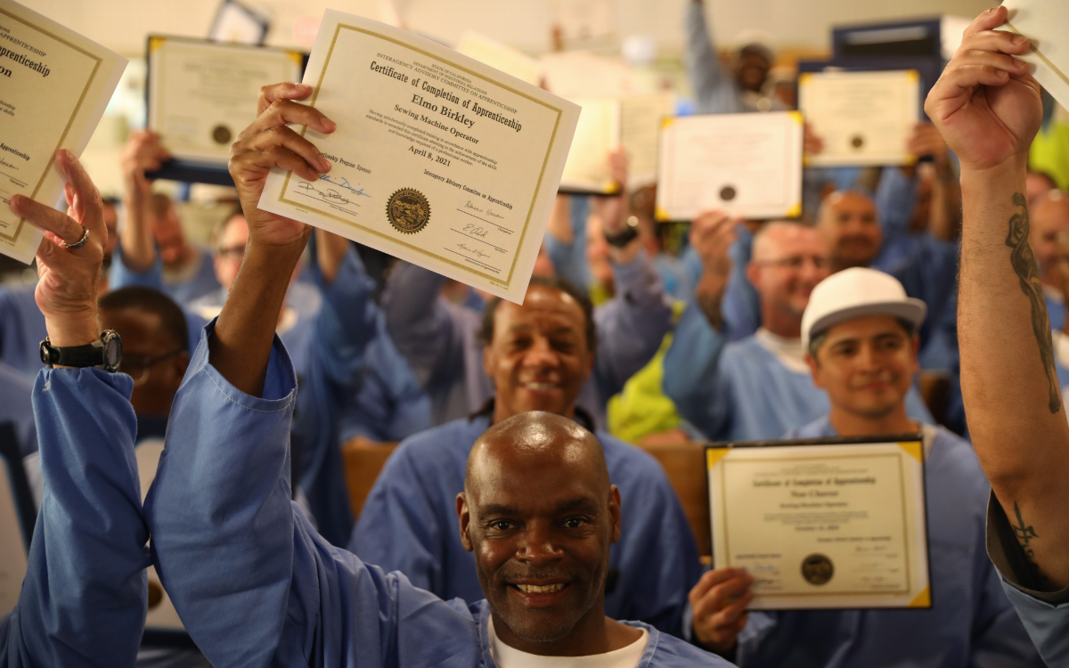Incarcerated people hold certifications and diplomas at a graduation for CALPIA at California Men's Colony (CMC) in San Luis Obispo.