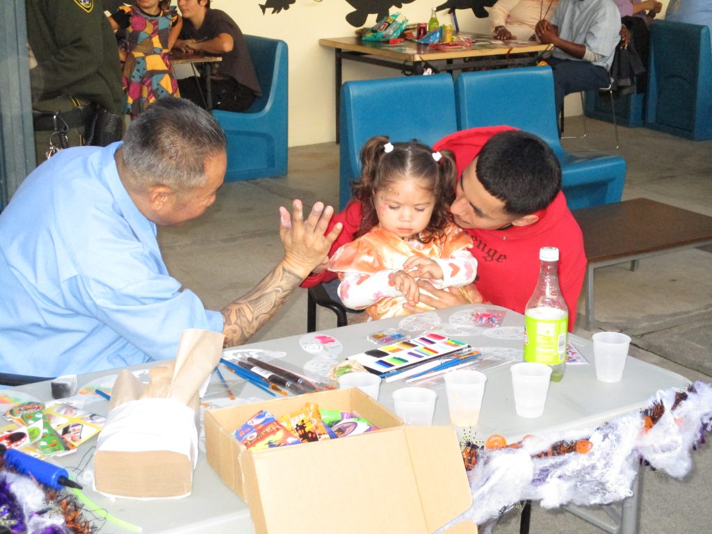 an incarcerated person high-fiving a trick-or-treater