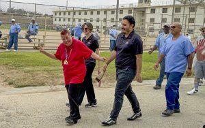 CTF-Soledad hosts a Flame of Hope Torch Run and Walk to benefit Special Olympics. The image shows a Special Olympics athlete leading the walk along with incarcerated people.