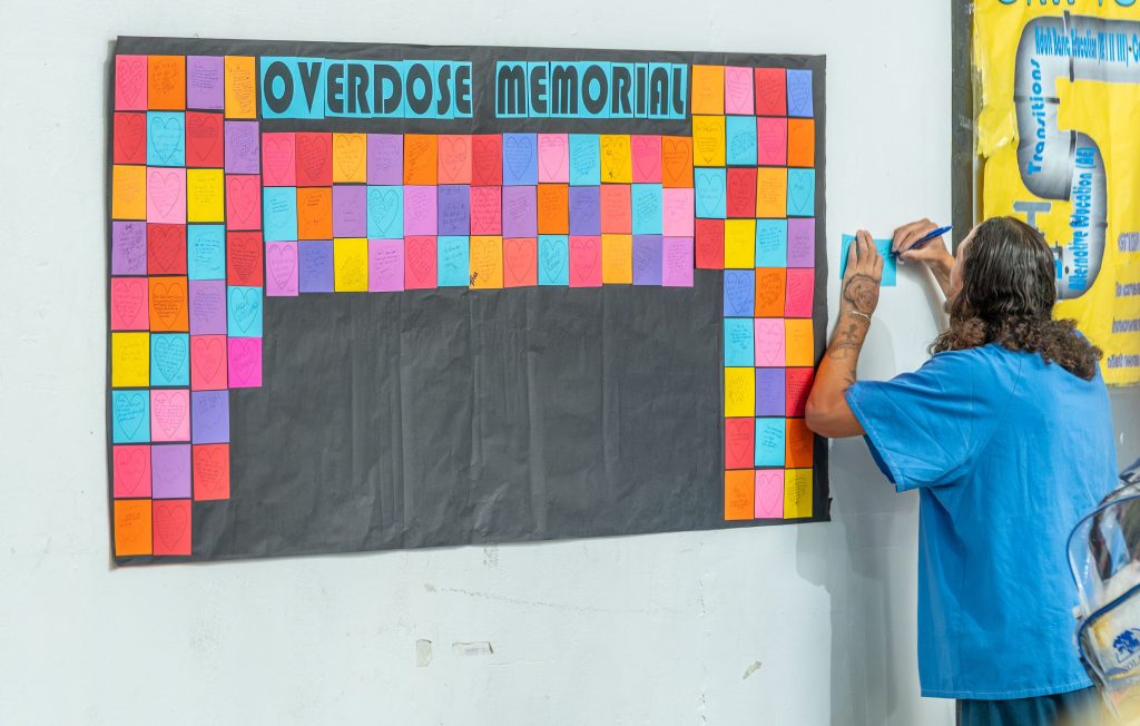 CMF incarcerated person writing on a memorial board for IOAD.