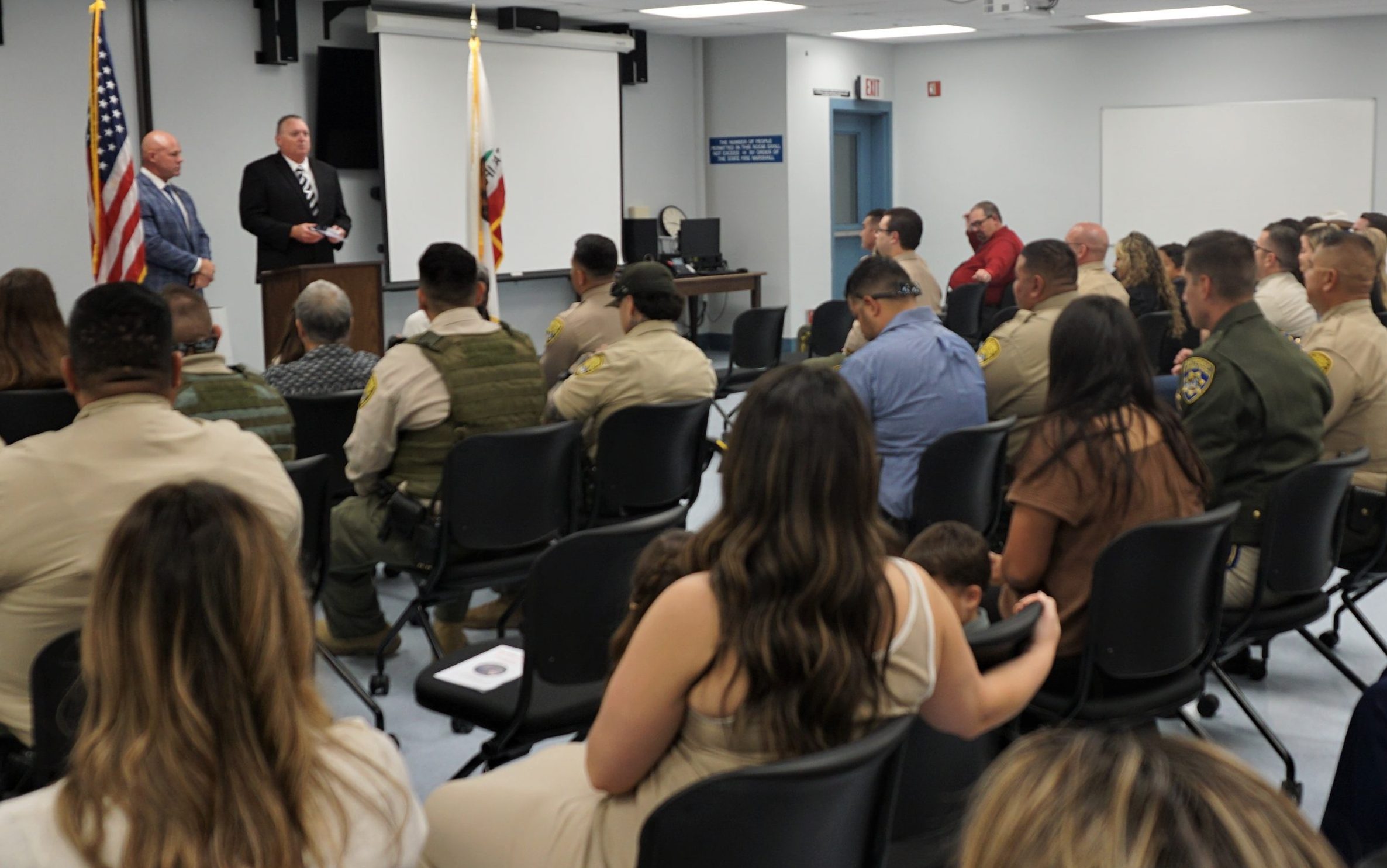 Warden and chief deputy warden at Kern Valley State Prison speak to staff and their families during a promotion ceremony.
