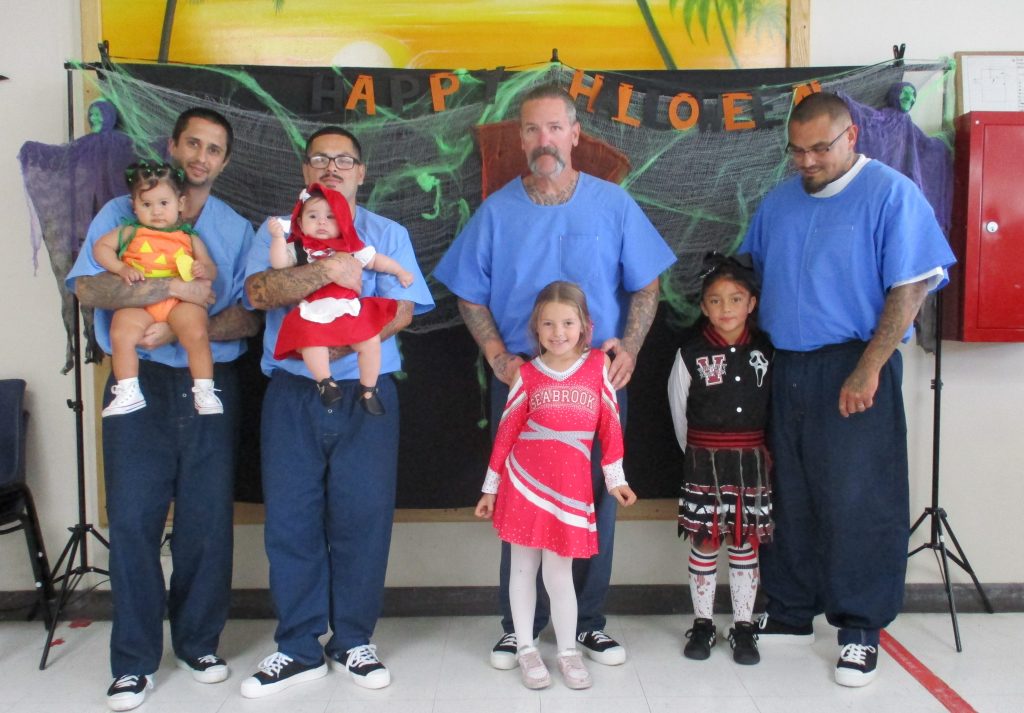 Incarcerated people and their visiting children wearing costumes for Halloween at Centinela State Prison.