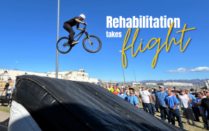 Ironwood State Prison rehabilitation event featured music, motorcycles and a BMX trick rider. The rider is seen in the air with the words "Rehabilitation takes flight" set against a blue sky while incarcerated people watch the BMX trick.