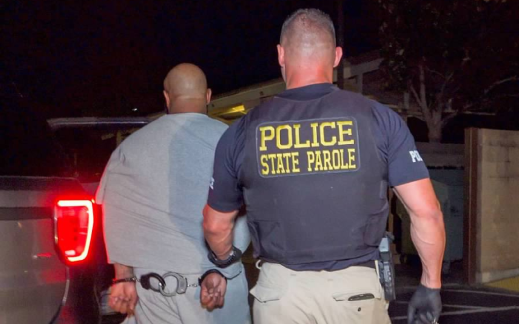 Operation Boo 2025 resulted in 94-percent compliance for those on parole supervision but there were 35 arrests made, such as this one shown with a parole agent escorting someone wearing handcuffs.