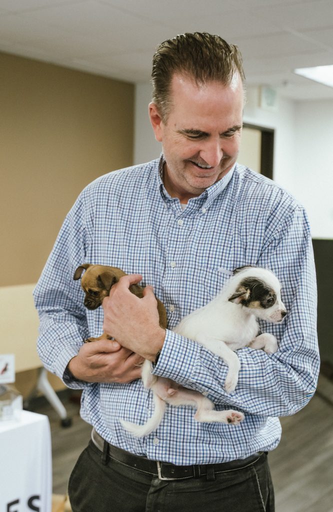 Our Promise 2025 event with Secretary Macomber holding puppies.
