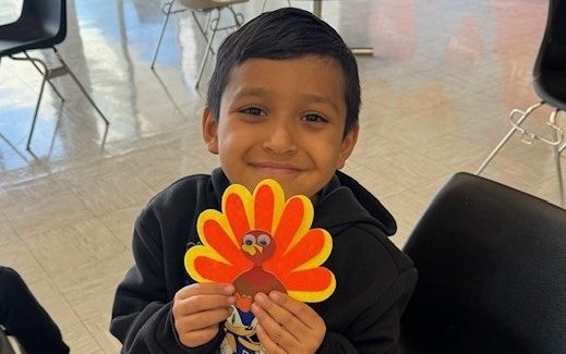 A child holds his crafted turkey at CCI visiting.