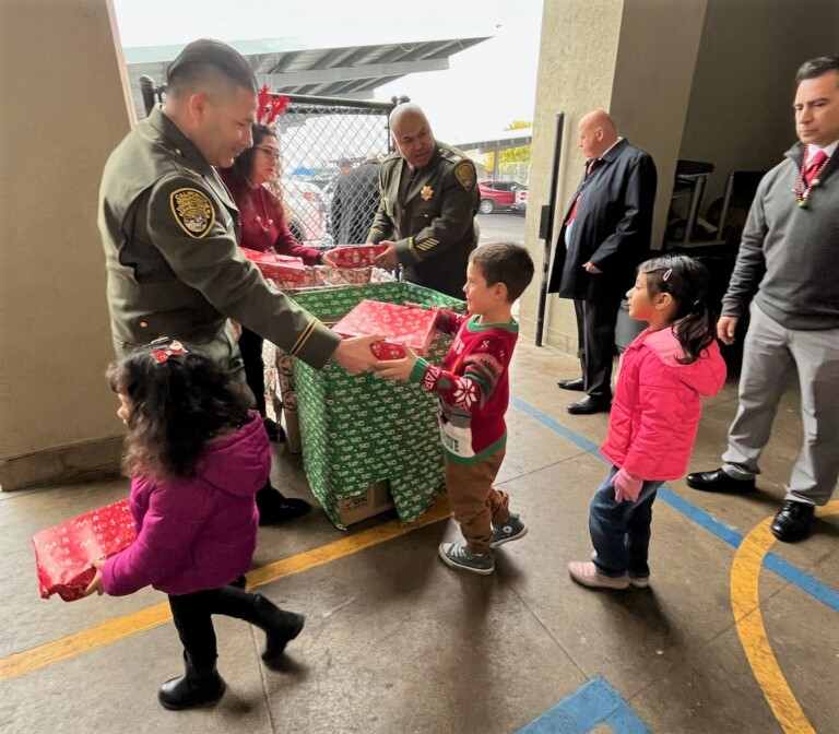 Staff member from CSP-Corcoran hands out gifts at Bret Harte Elementary School. 