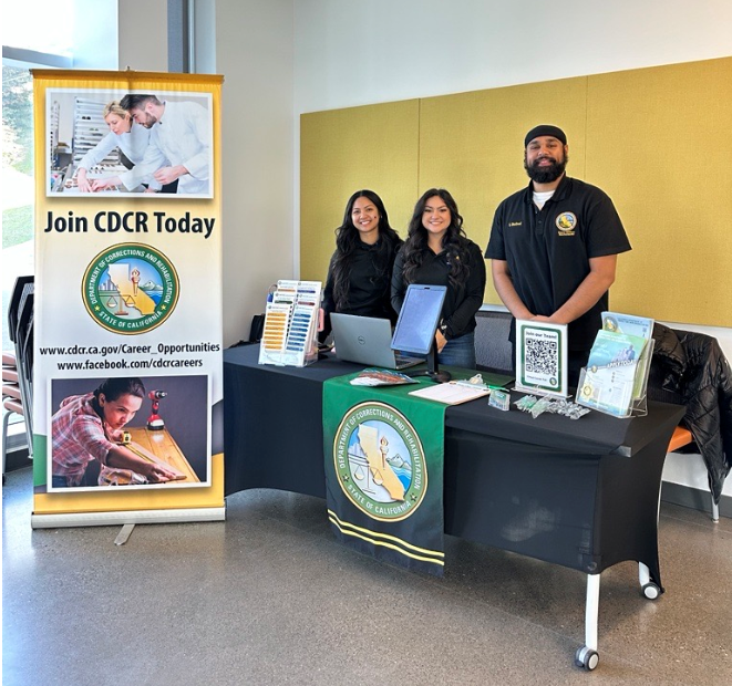 Recruiters behind a CDCR table, smiling