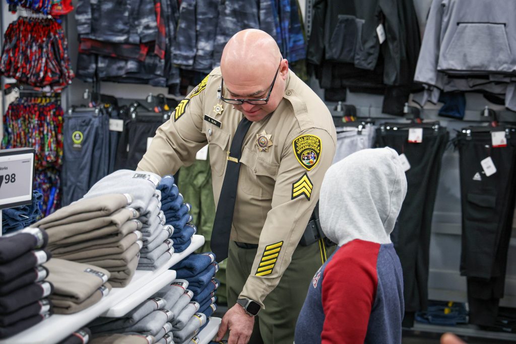 Child shopping with a cop, Sgt. A. Nuno, at Walmart in Galt, California, for the Christmas holiday season.