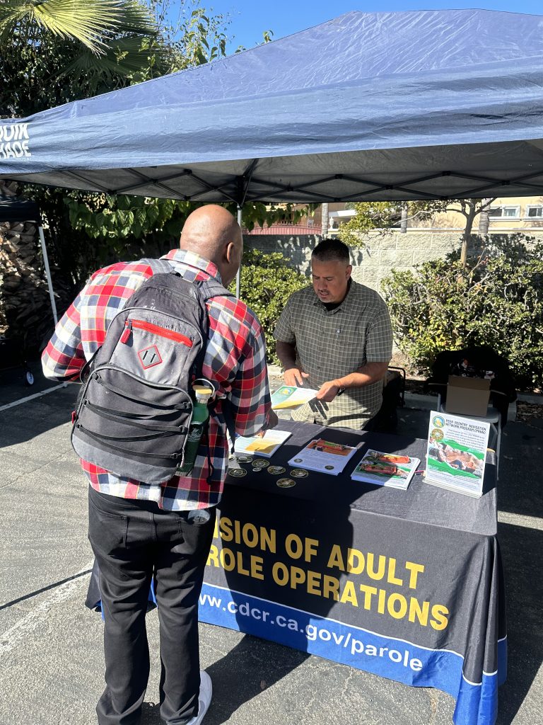 Foremerly incarcerated talking to DAPO staff at booth