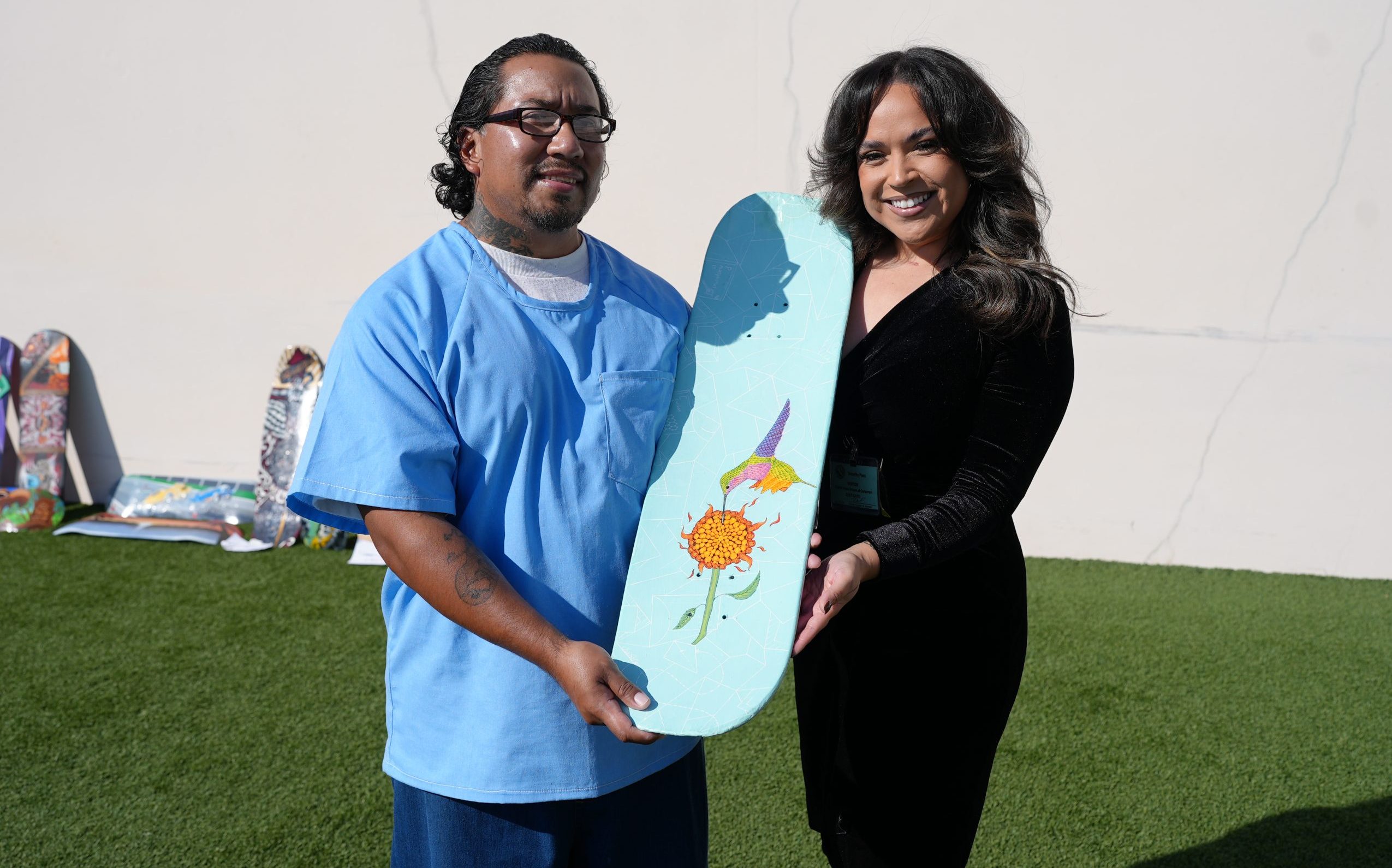An incarcerated artist holds his painted skateboard being donated to Fresno Skateboard Salvage.