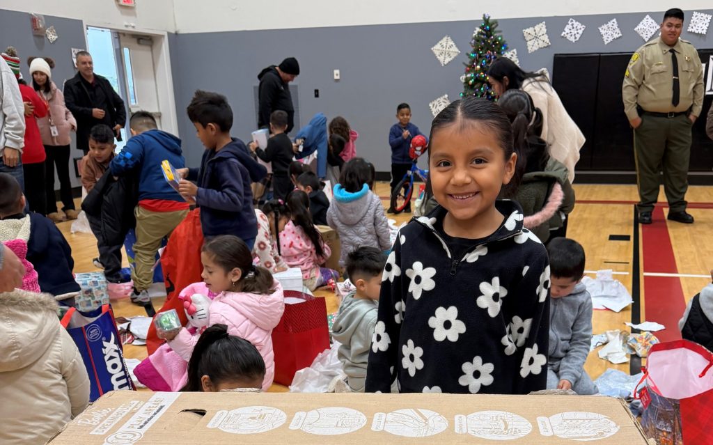 A child receives a Barbie Dream House during a holiday Christmas event with Kern Valley State Prison staff.