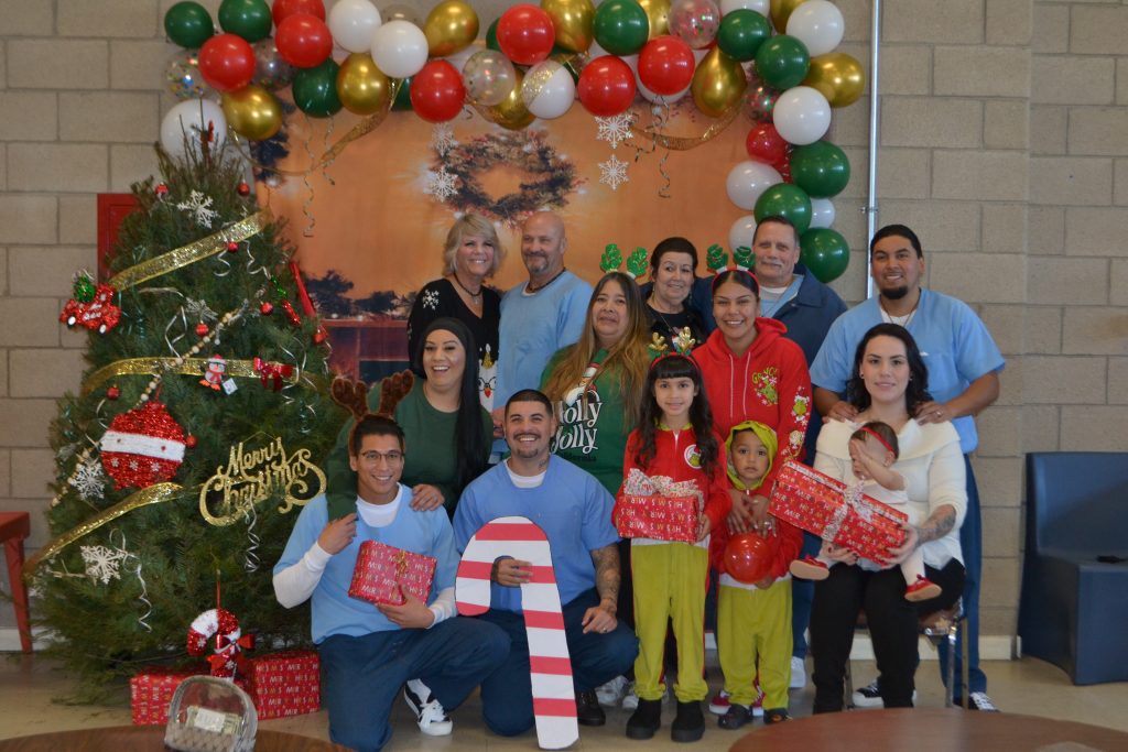Group photo of incarcerated people and their families visiting for the holidays at Valley State Prison in Chowchilla. 