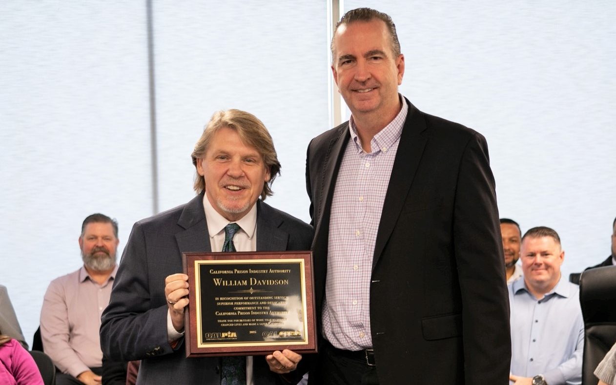 General Manager Bill Davidson holds his CALPIA retirement plaque alongside CDCR Secretary Jeff Macomber.