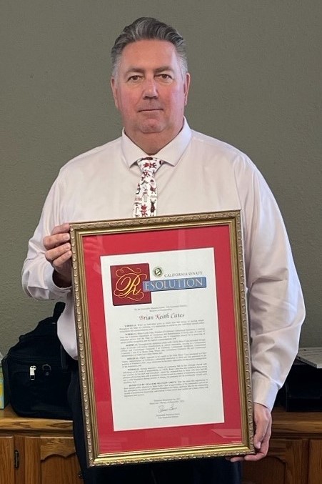 Retiring CCI Warden Brian Cates holds a senate resolution honoring his retirement.