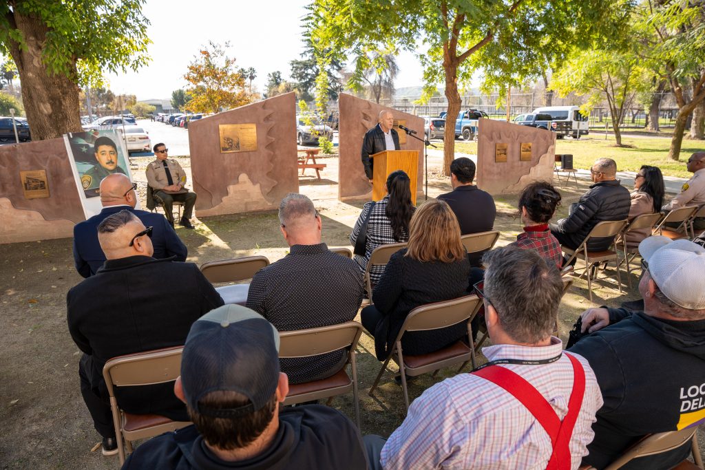 Staff and family at the memorial, listening to a speech