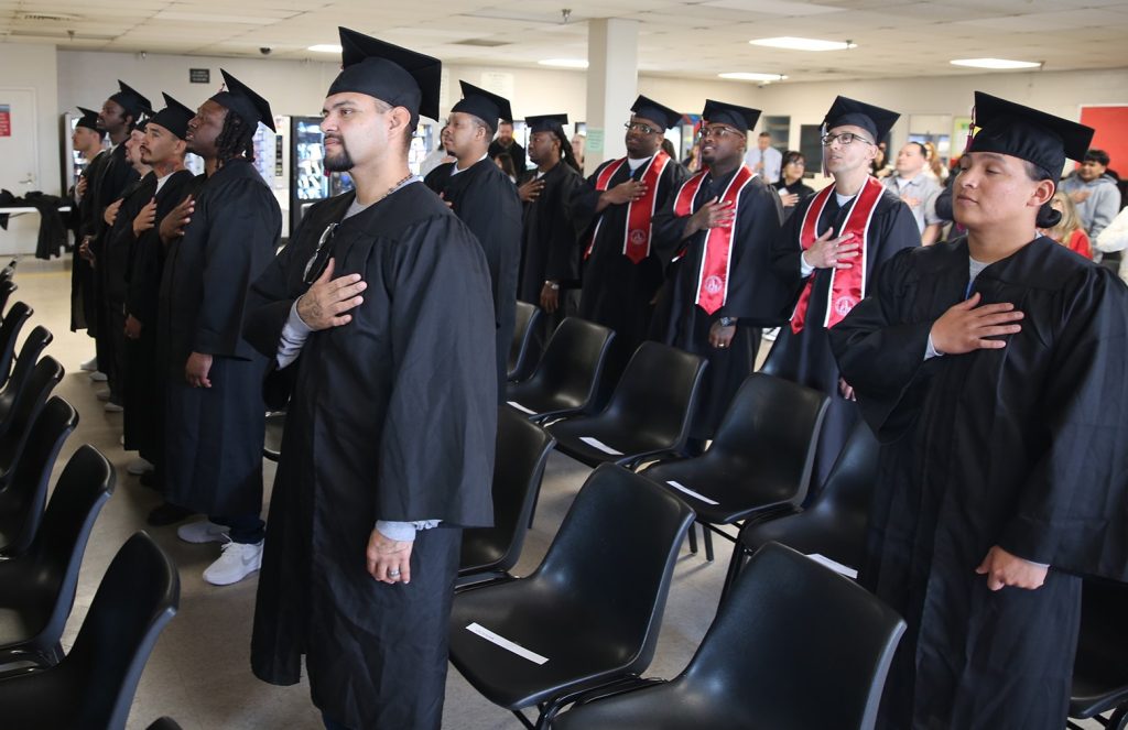 Incarcerated graduates stand to say the pledge of allegiance at WSP-RC.