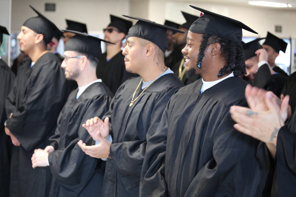 Incarcerated students applaud others as they receive their GEDs or college degrees.